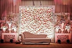 a white couch sitting in front of a wall covered with pink flowers and greenery