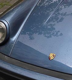 the front end of a blue sports car with a badge on it's hood