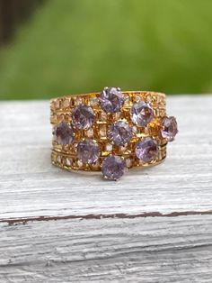 Unique 18 karat Yellow Gold Harem Stacking Ring featuring sparkly synthetic color changing sapphires (purple to turquoise color change) and diamonds METAL: 18 karat SIZE: 6 - sizing is not recommended due to nature of ring ERA: 1960s/1970s CONDITION: good vintage condition - stones securely set Kennedy's Cache sells curated antique and vintage pieces. Most have been preowned and loved and will have some signs of age and wear. We will disclose any flaws that would be out of the ordinary for age o Luxury Gold Amethyst Ring With Rose Cut Diamonds, Purple Sapphire Multi-stone Ring With Diamonds, Gold Sapphire Ring With Rose Cut Diamonds Cluster, Gold Amethyst Ring With Rose Cut Diamonds For Anniversary, Gold Amethyst Diamond Ring For Anniversary, Gold Amethyst Rings With Rose Cut Diamonds, Gold Multi-stone Amethyst Ring For Anniversary, Fine Jewelry Purple Cluster Rings, Purple Diamond Ring With Rose Cut Diamonds