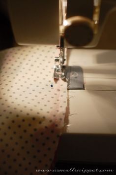 the sewing machine is next to the dotted fabric on the tablecloth that has been sewn