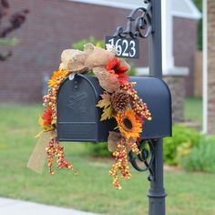 a mailbox decorated with sunflowers and fall leaves sits in front of a house