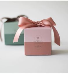 two boxes with pink and green ribbons tied to each other, one has a bow on the top