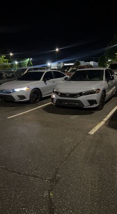 two cars parked in a parking lot at night