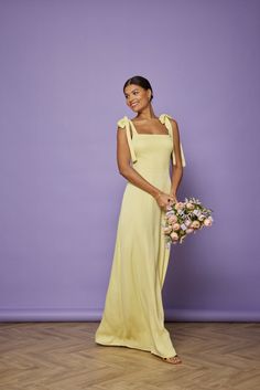 a woman in a yellow dress holding a bouquet of flowers and posing for the camera