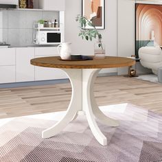 a white table with a wooden top in a living room next to a kitchen area