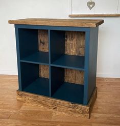 a blue bookcase with wooden shelves on the top and bottom, in front of a white wall