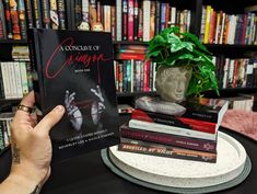 a person holding up a book in front of a bookshelf