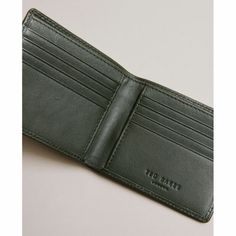 Ted Baker HACKIN Dark Green Trunk Lock Leather Bifold Wallet
Store your cash and cards in one convenient place with this ultra-stylish and compact wallet from Ted Baker. Slim enough to slip into your pocket, this wallet is the ultimate accessory to keep you organised on the go!
Made from genuine bovine leather, this wallet is dark green in colour and features rounded corners along with a branded brass metal stud detail on the front. The bifold wallet is perfect for keeping you organised, when you open up the wallet there are eight horizontal slots for cards, two small vertical slots, as well as a large pouch for notes! The Ted Baker logo has been debossed on the interior completing the chic design.
The dark green bifold wallet makes a wonderful gift for friends and family for Christmas, bi Baker Logo, Large Pouch, Compact Wallet, Leather Bifold Wallet, Bifold Wallet, Brass Metal, The Chic, Chic Design, Rounded Corners