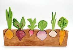 a wooden planter filled with different types of veggies on top of a white surface