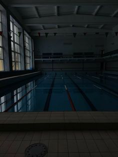 an empty swimming pool in the middle of a building with large windows and tiled floors