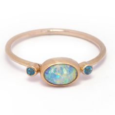 A captivating Australian boulder pipe opal with a vibrant overall aqua hue that displays gorgeous flashes of electric green and lilac.  Measuring 8.3 x 5.6 mm this 0.75 carat rainbow beauty is bezel set in 14k yellow gold with a sterling silver back. A duo of 2 mm faceted apatite gemstones add a playful pop of color an Oval Blue Opal Ring In 14k Gold, Laos Jewelry, Green And Periwinkle, Rainbow Beauty, Electric Green, Dream Future, Rings And Bracelets, Stacking Bands, Australian Boulder Opal