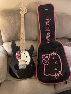 an electric guitar and hello kitty case sitting on a couch next to eachother