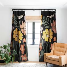 a living room with a chair, rug and window in front of the curtain that has flowers on it