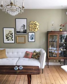 a white couch sitting in a living room next to a wooden table and chandelier