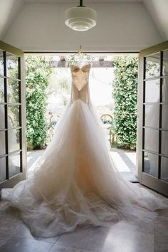 a wedding dress hanging in an open doorway