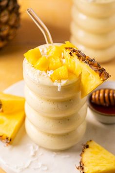 a dessert with pineapples and whipped cream on a plate next to some honey