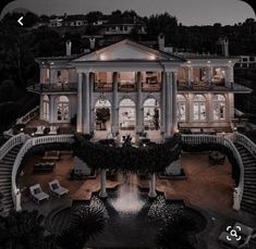 an aerial view of a mansion at night with the lights on and stairs leading up to it