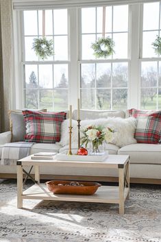 a living room filled with furniture and pillows on top of a rug next to a window