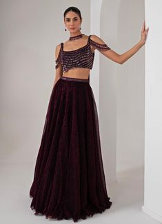 This stunning Black Platinoir Crepe Embellished Lehenga Set exudes modern elegance and glamour. Crafted from luxurious platinoir crepe, the black lehenga features a dramatic full-length skirt with all-over metallic brazen fall detailing, adding a shimmering effect with every movement. The crystal-embroidered waistband accentuates the waist, offering a refined silhouette. Teamed with a cold shoulder blouse, the ensemble reaches new heights with its halo crystal tassel embellishments, delivering a unique and stylish twist. The look is completed with a choker-style embellished dupatta, perfectly complementing the outfit with a sophisticated touch. Ideal for Cocktail parties, Sangeet nights, or evening events, this lehenga set is designed for those who wish to make a bold and fashionable state Cold Shoulder Indian Dress, Black Indowestern For Women, Cold Shoulder Blouse Indian, Sangeet Night Outfit, Shoulder Blouse Designs, Cold Shoulder Blouse Designs, Embellished Lehenga, Full Sleeve Top, Black Lehenga