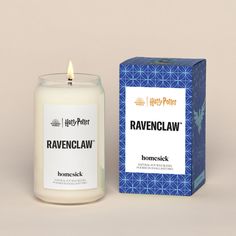 a candle that is next to a box on a table with the words ravenclaw printed on it