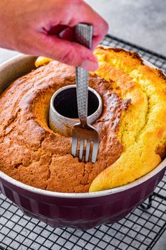 someone is cutting into a cake with a knife and fork in it on a cooling rack