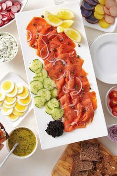 a platter with sliced up salmon, cucumbers, and other foods on it