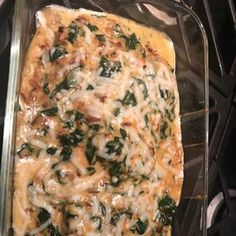 a casserole dish with spinach and cheese on top in a glass pan