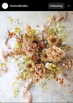 a bunch of flowers that are on top of a white table cloth and some kind of ribbon