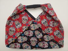 a red and black bag with skulls on it's front, sitting on a white surface