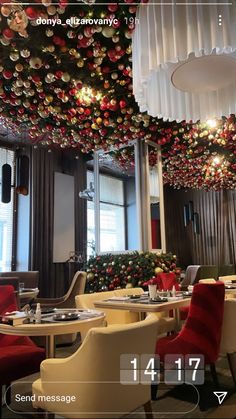 a restaurant decorated for christmas with red and white decorations hanging from the ceiling over tables