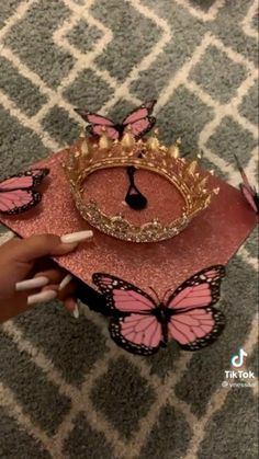 a person is holding a pink and gold tiara on top of a red tray