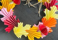 colorful paper flowers arranged in the shape of a wreath on top of a black surface