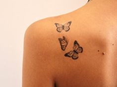 the back of a woman's shoulder with three butterflies on her upper arm and chest