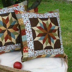 two pillows sitting on top of a blanket next to an apple