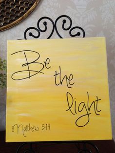 a yellow sign with the words be the light written in cursive writing on it