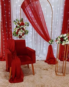 a red chair sitting in front of a white backdrop with flowers on top of it