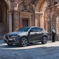 the new alfa suv is parked in front of an old building with stone pillars and arched doorways