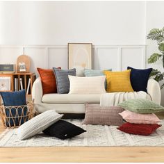 a living room filled with lots of pillows on top of a white rug next to a couch