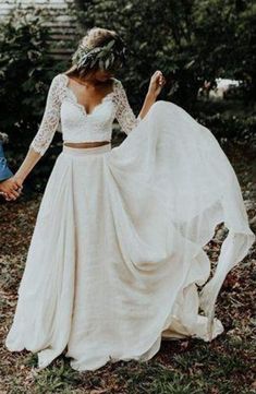 a woman in a white dress is walking through the woods with her hands on her hips