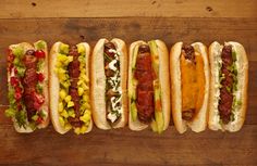 five hot dogs lined up on top of each other with condiments and toppings