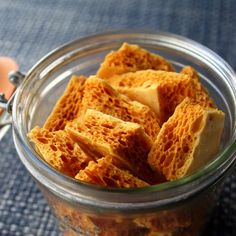 a glass jar filled with crackers sitting on top of a blue cloth covered table