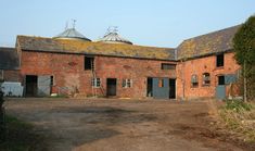 an old red brick building with two chimneys on the roof and one door open to let in light