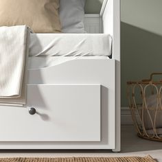 a close up of a bed with a white headboard and foot board next to a basket