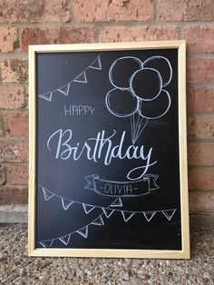 a chalkboard sign with the words happy birthday written on it and balloons in the air