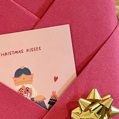 an envelope with a christmas kisses card on it next to a gold gift bow