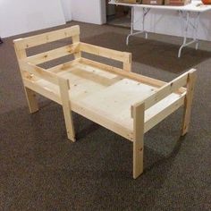 a wooden bed frame sitting on top of a carpeted floor next to a table