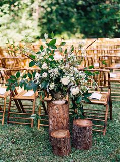 an outdoor ceremony setup with wooden chairs and floral centerpieces