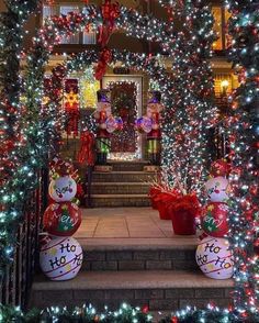 christmas lights decorate the front steps of a house with holiday decorations on it and wreaths