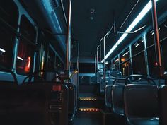 the interior of a public transit bus with its lights on and empty seats at night