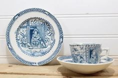 two blue and white plates sitting on top of a wooden table next to a bowl